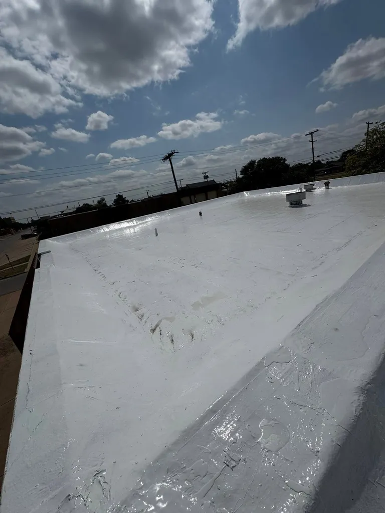 Fresh white roof coating on a flat commercial roof with parapet walls